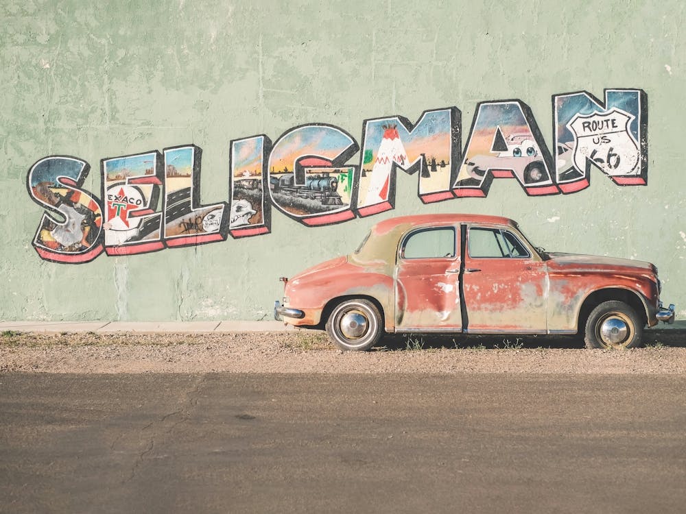 Route 66, USA I Voiture américaine vintage devant un mur de typographie street art à Seligman en Arizona dans la campagne américaine rétro vintage lors d'un road trip sur l'historique Route 66 en Californie