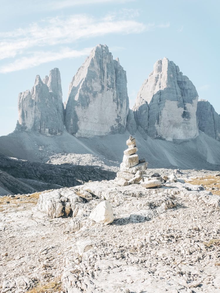 Dolomites, Italy I Tre Cime di Lavaredo mountain landscape photography with cairn in foreground and rocky peaks the authentic, geometric, raw mineral wilderness nature of the Italian Alps during summer