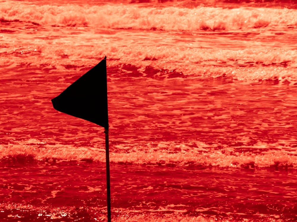 Black Warning Flag Marking The Limit Of The Safe Swimming Area At A Beautiful Beach With Blue Sky And A Turquoise Sea In Israel