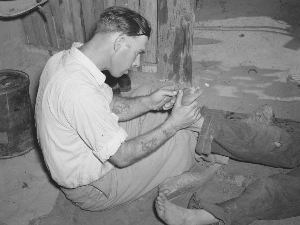 Resident Of Mays Avenue Camp Taking Out A Piece Of Glass From Boy S Foot, Oklahoma City, Oklahoma By Russell