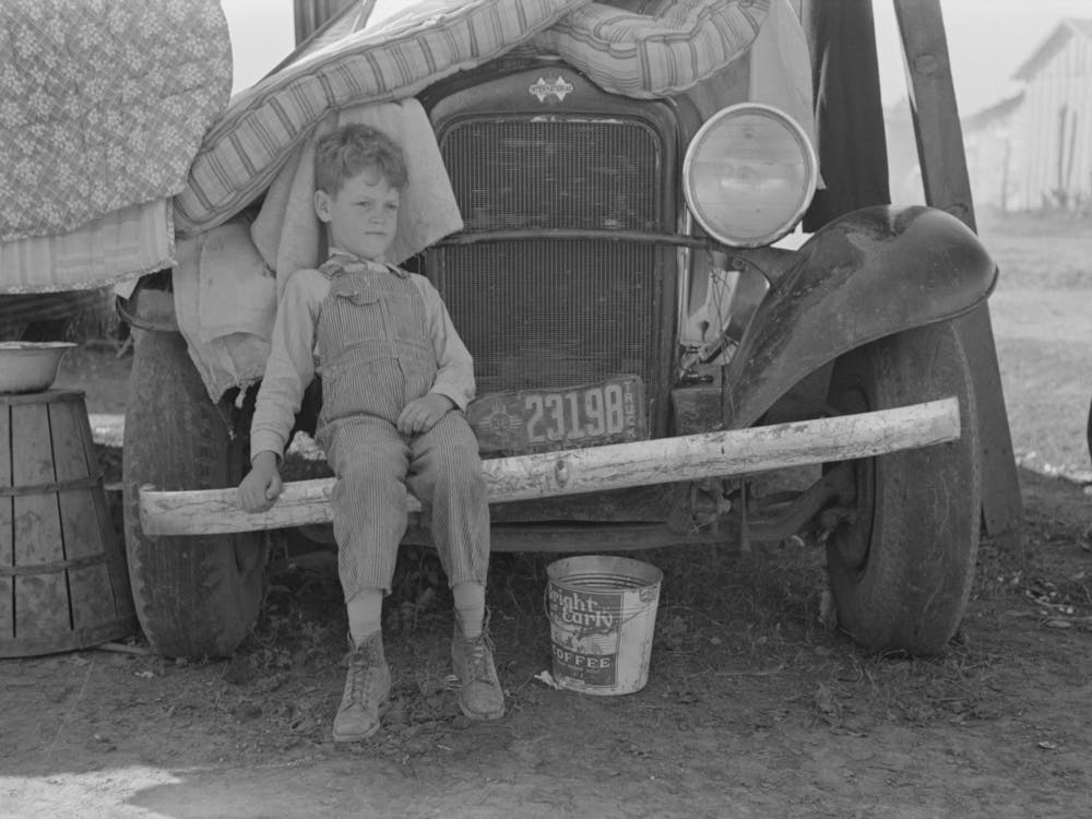 Son Of Migrant Sitting On Bumper Of Their Truck, Weslaco, Texas, Notice New Mexico License By Russell Lee