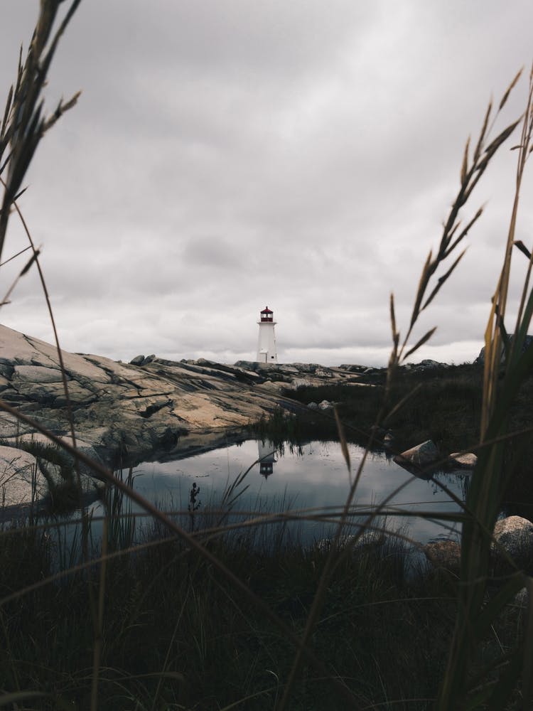Peggys Cove Lighthouse With Pond Mirroring The Lighthouse Nova Scotia Atlantic Ocean Moody