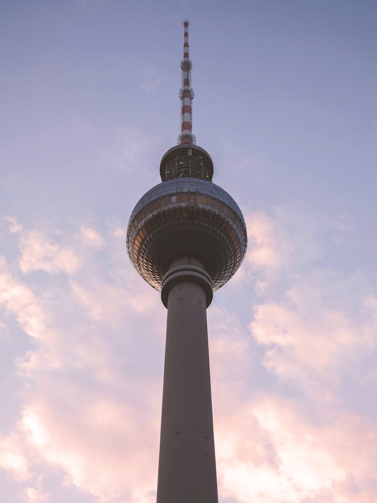 Berlin, Allemagne I Silhouette minimaliste de la Tour Fernsehturm au coucher du soleil avec un ciel rose-bleu pastel pour un paysage urbain géométrique et abstrait photographié à l'heure dorée avec une photographie industrielle urbaine poétique