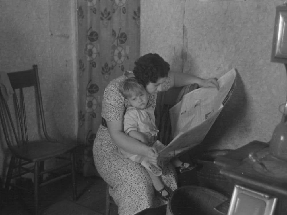 Child On Lap Of Mother Reading The Newspaper, Nissen Shack Near Dickens, Iowa By Russell Lee