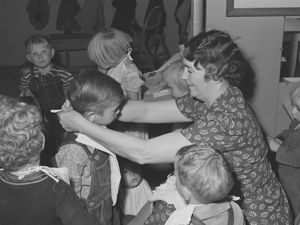 Wpa (Work Projects Administration) Teacher At The Nursery School Puts On Bibs Of Her Charges At The Fsa