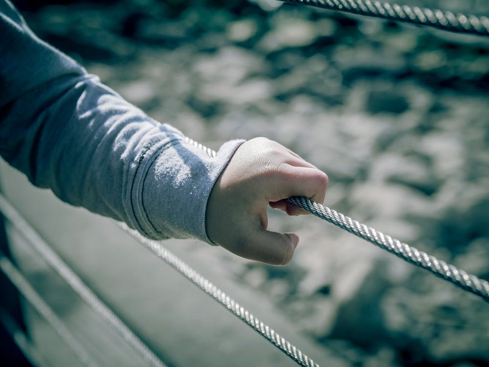 Young Boy Hand Holding Metal Wire Fence